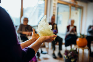 Die Besucher der Sophia-Tagesbetreuung sitzen in einem Kreis und halten der Reihe nach ein leichtes Tuch, das zu einer Art Ball geformt ist.