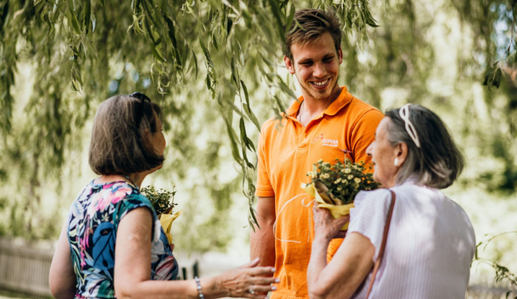 Drei Personen unterhalten sich unter einem Baum