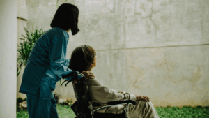 Frau in einem Rollstuhl wird von einer anderen Frau geschoben