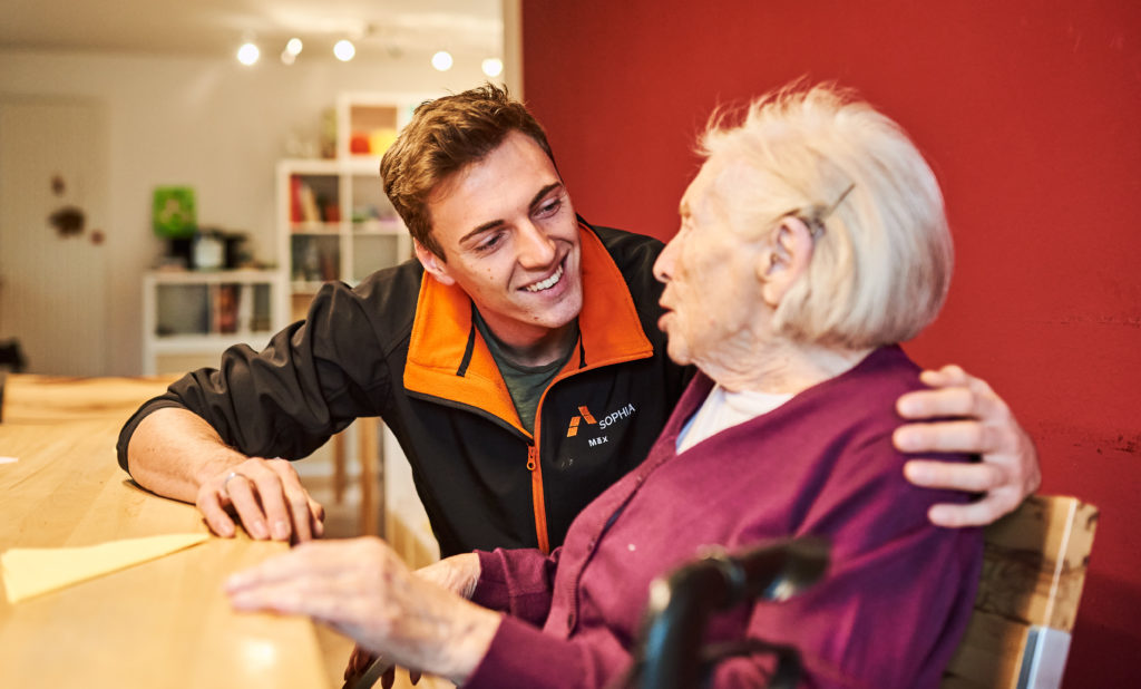 Betreuer unterhält sich mit älterer Frau in einer Tagesbetreuung